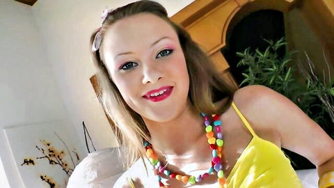 Smiling Caucasian woman in yellow top with beaded necklace, solo masturbation tease