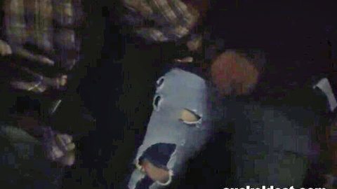 Masked participant in blue animal mask with older man in explicit threesome scene