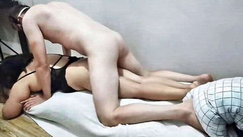 Naked slim man fucks Asian woman in black strappy lingerie doggystyle while cuckold in plaid shorts watches