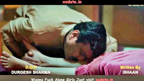 Clothed Indian man kneeling submissively face down on pink bed with 'wanna fuck alone girls' promo text