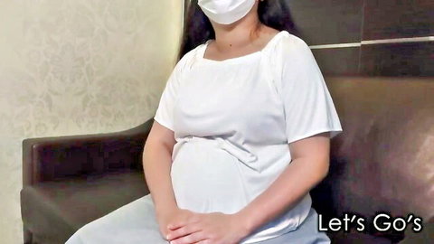 Pregnant Asian woman in white top and mask, sitting casually for JAV preview