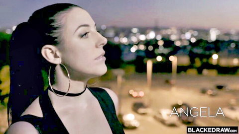 Angela White in low-cut black top, seductive pose with city skyline