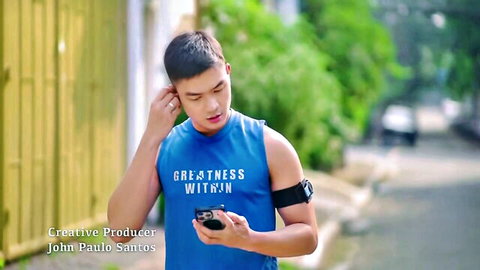 Handsome Filipino actor John Paulo Santos in casual tank top, holding phone outdoors