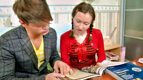 Bridgette Vericheva in pigtails and red schoolgirl sweater with male partner over book
