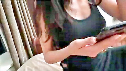 Brunette woman in low-cut black tank top showing cleavage, holding tablet