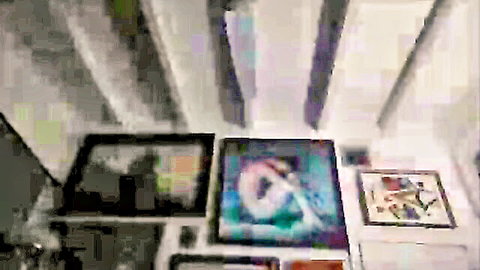 Blurry upward view of framed abstract colorful paintings on white shelves
