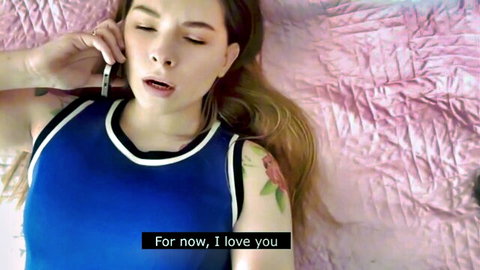 Blonde babe in tight blue tank top lying on pink bed talking passionately on phone