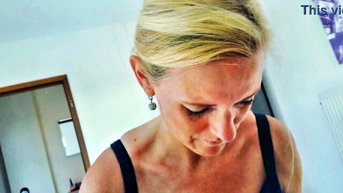Blonde amateur in black tank top looks down smiling in living room POV