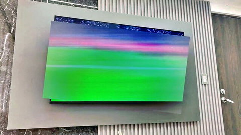 Modern framed TV screen displaying vibrant abstract purple and green gradient artwork on marble wall
