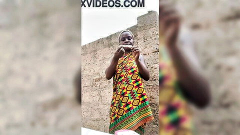Mature ebony woman in colorful African dress posing outdoors in Ghana