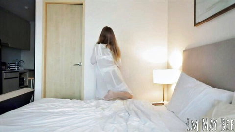 ImMayBee kneeling in sheer white robe on bed, teasing view from behind