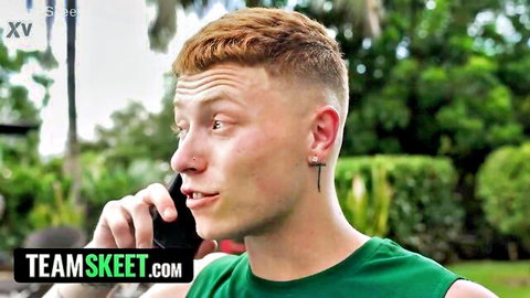 Ginger-haired guy in green tank top talking intensely on phone outdoors