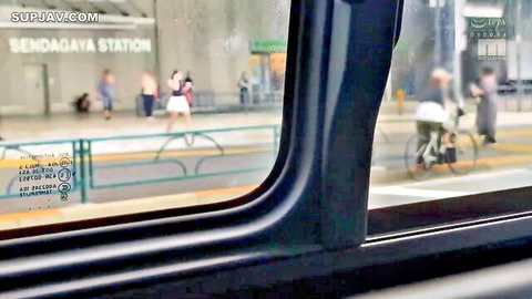 View from train window at Sendagaya Station platform with pedestrians and cyclist in urban Tokyo scene