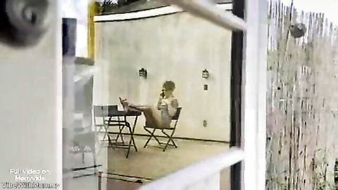 Blurry amateur woman sitting on outdoor patio chair with legs extended talking on phone