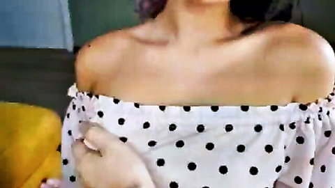 Petite babe in polka dot off-shoulder top showing deep cleavage and smiling seductively
