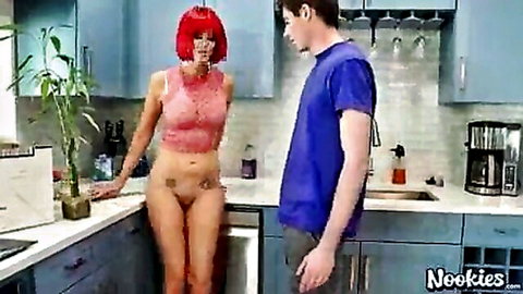 Redhead MILF with big tits exposes shaved pussy leaning on kitchen counter