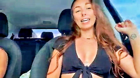 Ariel Siren redhead smiling in car with deep cleavage and arm tattoo