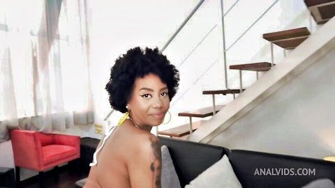 Smiling ebony woman with curly hair, topless and tattooed