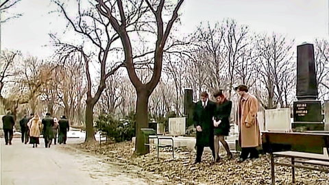 Elegant women in coats and hats walking in foggy autumn cemetery scene