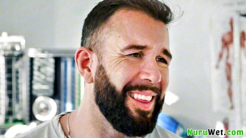 Handsome bearded man smiling in massage room with anatomical models