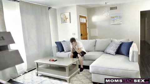 Shy teen boy covering face on couch in Moms Teach Sex taboo living room scene