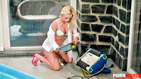 Krystal Kaytlin in open white shirt and green bikini kneeling by pool robot