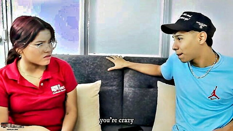 Red-haired Latina step-sister in glasses and red polo talks to step-brother on couch