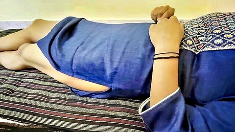 Seductive woman in blue dress lying on bed, legs exposed, intimate pose