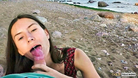 Young brunette teen licks pink dildo with tongue out on rocky beach outdoor POV blowjob