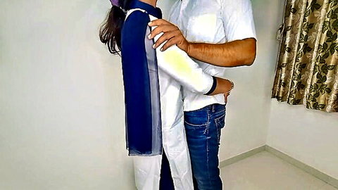 Indian couple in salwar kameez and jeans hugging intimately from behind in bedroom