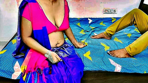 Mature Indian wife in pink low-cut blouse and blue saree exposing cleavage and belly next to husband on bed