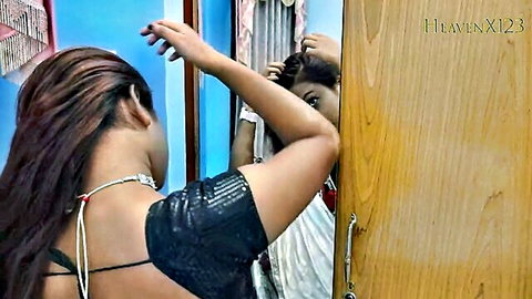 Sexy Indian bhabhi in black sequin blouse and white saree adjusting long hair in mirror