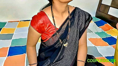 Desi Indian woman in black saree and red blouse, seductive pose on bed