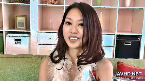 Smiling Asian beauty in feathered dress showing cleavage