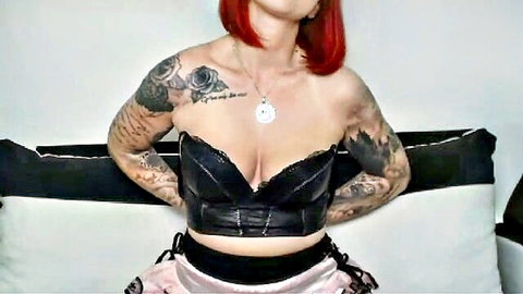 Tattooed redhead with huge cleavage in black leather corset and pink panties teasing seductively