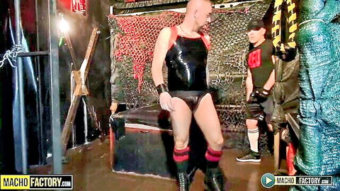 Two muscular men in latex harness and gear posing in BDSM scene