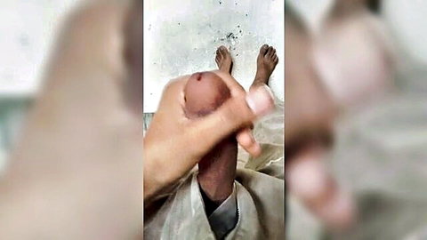 Blurry amateur handjob on brown-skinned man's erect penis, feet visible