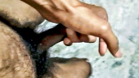 Brown hand gripping dark erect cock with pubic hair, amateur tease