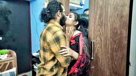 Indian couple passionately kissing in red saree near wardrobe sensual foreplay