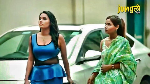 Two curvy Indian women in blue cutout dress and green saree posing by car