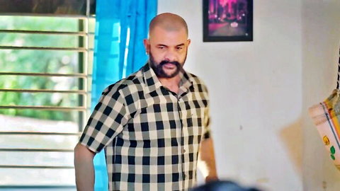 Bald Indian man with beard in checkered shirt, intense expression