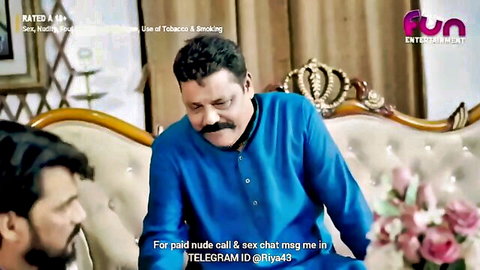Indian mature man in blue kurta chats with younger man on sofa