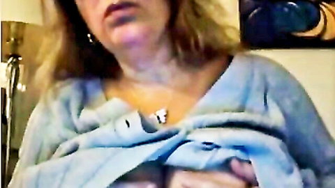 Mature blonde woman with messy hair exposing cleavage in open blue sweater
