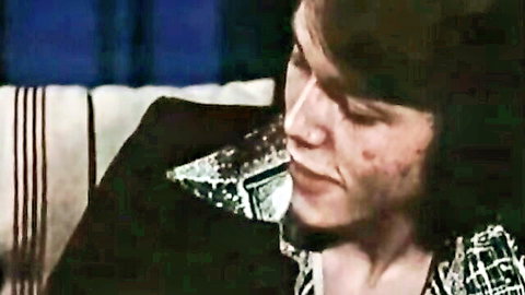 Close-up of vintage hairy man's intense face with mustache and shaggy hair in sparkly jacket