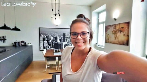 Smiling brunette babe in loose white tank top takes kitchen selfie showing cleavage