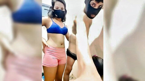 Masked South Asian woman in blue bra and pink shorts poses sexy with boyfriend in black underwear bathroom mirror selfie