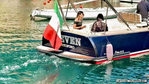 Two sexy brunettes in lace tops lounging on luxury speedboat with Italian flags in turquoise waters