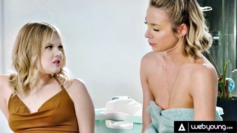 Petite blonde teen stares lustfully at topless blonde with towel in laundry room