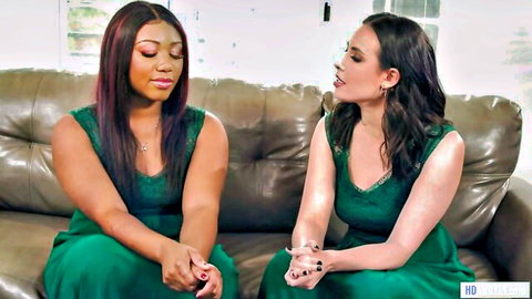 Casey Calvert and Chanell Heart as bridesmaids in green dresses, intimate lesbian moment