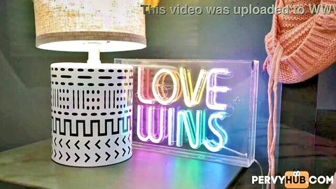 Cozy room setup with glowing 'LOVE WINS' neon sign, lamp, and pervyhub watermarks